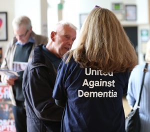 Woman talking to man - her t-shirt says United Against Dementia
