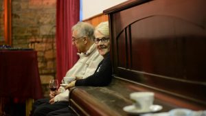 A lady smiles to camera round a piano