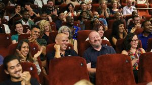 A group of people sitting in red cinema seats