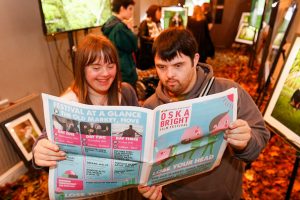 Two people read a magazine at Oska Bright Film Festival