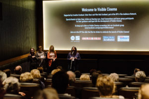Image of audience of "Visible Cinema" in cinema with speakers and sign language interpreters.