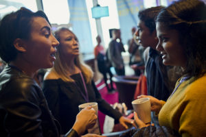 People talking holding tea mugs at an event.