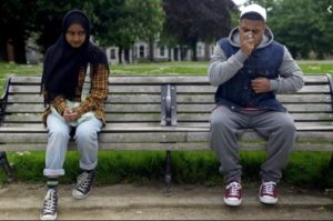 Still from short film: Shia // Sunni by Adam Tyler of two teenagers sitting on a bench