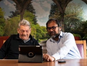 One older and one younger person smiling at a tablet screen
