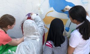 Four people painting a mural on a wall