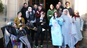 Group of young people in spooky costume outside a mansion.