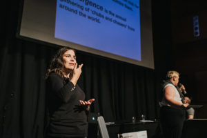 An interpreter using sign language on a stage next to a person with a microphone.