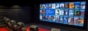Cinema screen with array of Blu-Ray film covers and cinema seats in front of it.