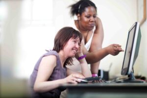 Two people smiling and looking at a computer