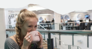 Woman drinking a cup of tea in an open plan office