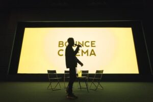 Silhouetted man stands in front of screen stating Bounce Cinema